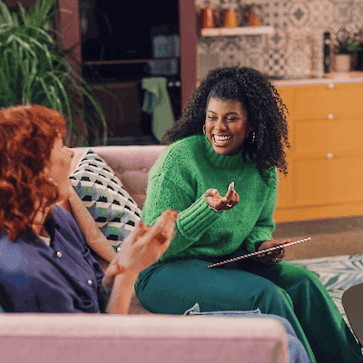 Two women smiling and talking together on a sofa